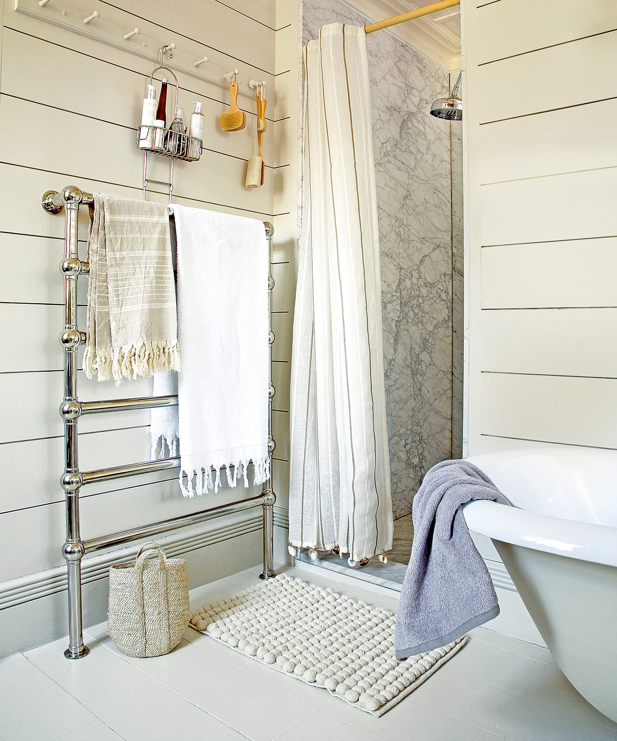 A bathroom with cream painted, horizontal wood paneled walls and a marble shower