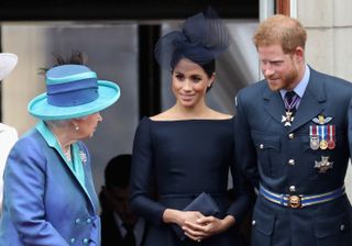 (L-R) Queen Elizabeth II, Meghan, Duchess of Sussex, Prince Harry, Duke of Sussex watch the RAF flypast on the balcony of Buckingham Palace, as members of the Royal Family attend events to mark the centenary of the RAF on July 10, 2018 in London, England.