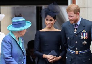 (L-R) Queen Elizabeth II chats to Meghan, Duchess of Sussex and Prince Harry, Duke of Sussex whilst gathered to watch the RAF flypast on the balcony of Buckingham Palace, to mark the centenary of the RAF on July 10, 2018 in London, England.