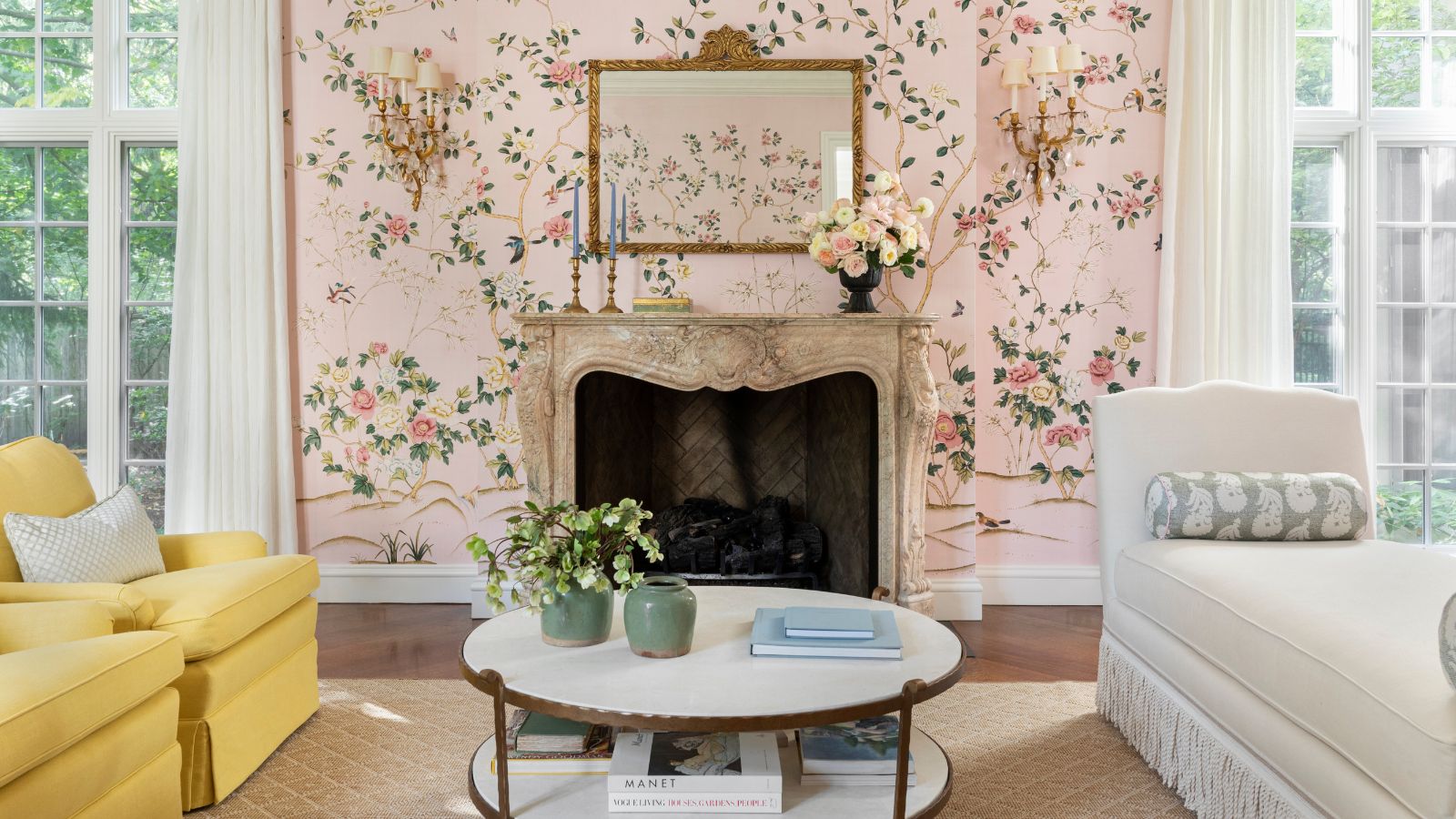 traditional grand living room with two french glass doors and a ornate fireplace with a pink floral mural wallpaper behind