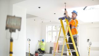 Electricians fitting new lights in white kitchen