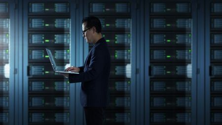 man working on laptop in data center