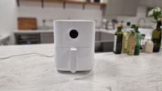 Xiaomi air fryer sitting on a white marble counter with bottles of oil behind it