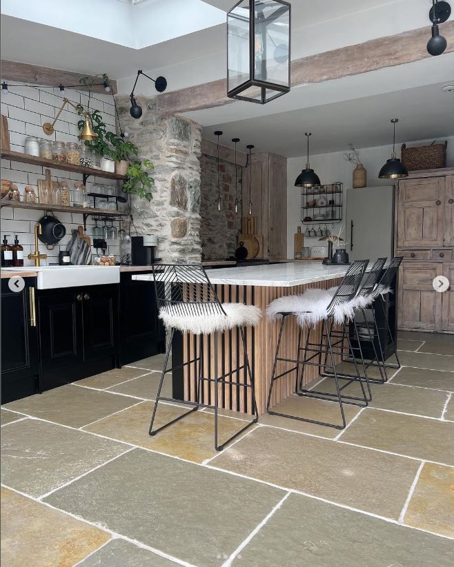 A kitchen seen from a different angle with the sink visible behind a large kitchen island