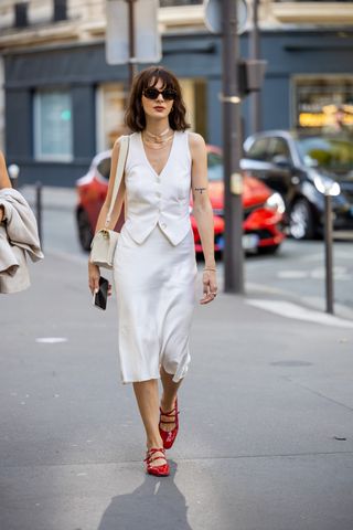 woman wearing a tailored vest, skirt, and ballet flats