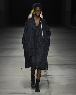 Woman model in black outfit walking on runway at Milan Fashion Week