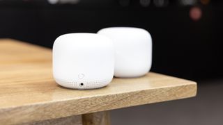 Two Google Nest smart speakers on a wooden table