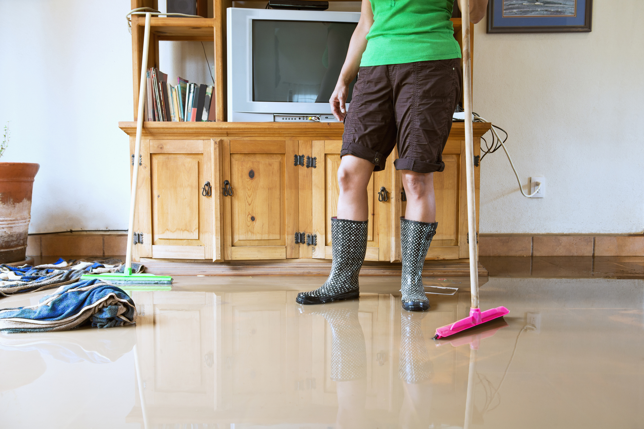 A woman cleaning up flood water in a living room. 