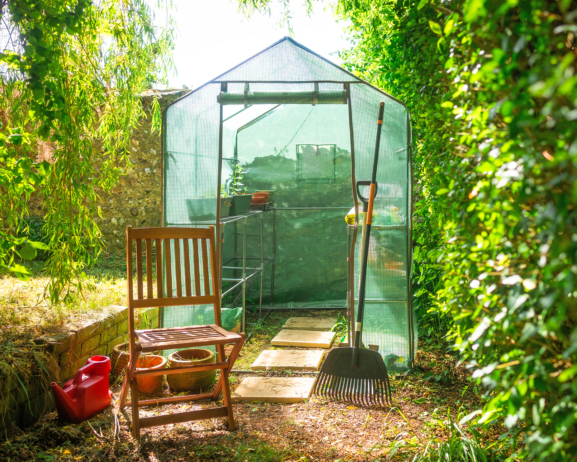 Portable greenhouse with chair and rake