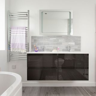 bathroom with white wall grey designed floor towel rails wash basins and cabinets