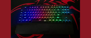 black compact keyboard with wrist rest against black and red background