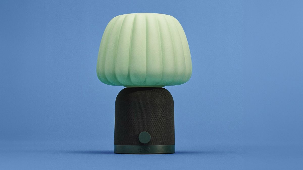 En gr&oslash;nn IKEA-lampe mot en bl&aring; bakgrunn.