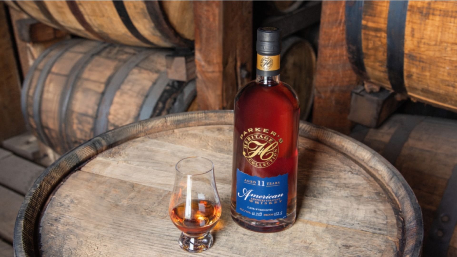 AN IMAGE OF THE PARKER HERITAGE COLLECTION WHISKEY ON A BOURBON BARREL WITH A TASTING GLASS OF WHISKY NEXT TO IT