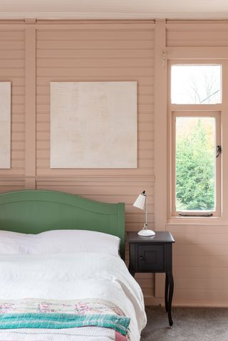 A pink bedroom with a window and green headboard