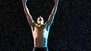 Male athlete raising arms in victory in rain – tips for running at night on trails