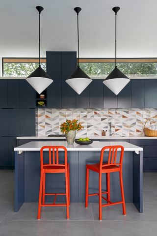 A blue kitchen with bright orange counter stools