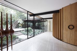 bridging boyd by jolson, a modernist house refreshed with white walls, black framing and details and a overgrown leafy garden seen through large glazing