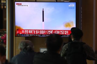 People watch a TV at the Seoul Railway Station in South Korea showing a file image of a North Korean missile launch on March 24, 2022.
