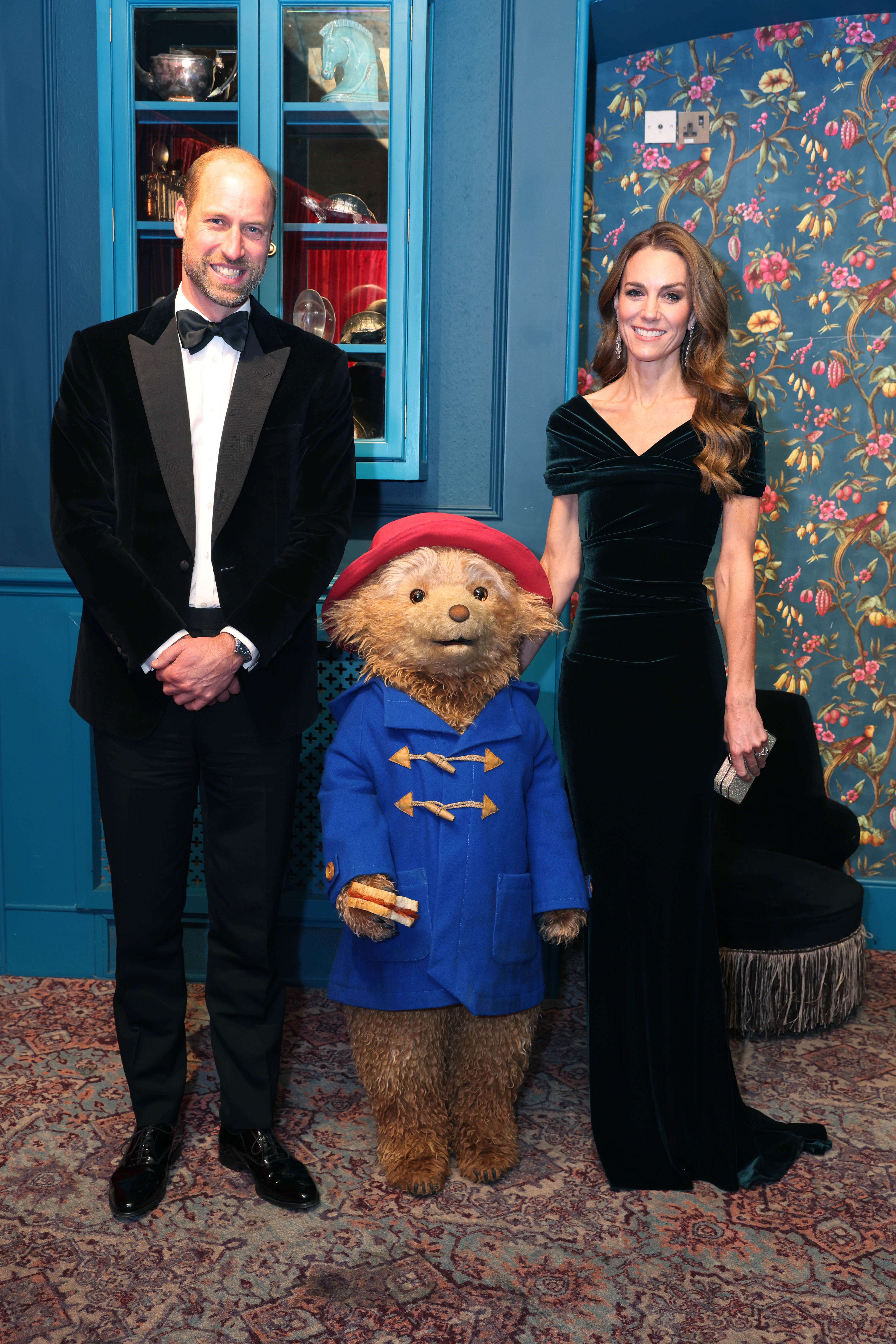 Prince William and Kate Middleton wearing evening wear and posing with Paddington Bear