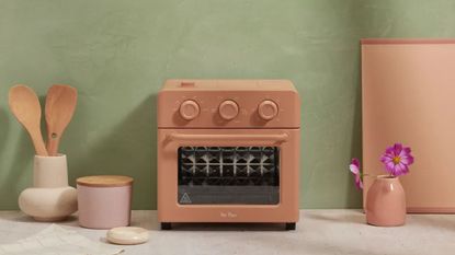 One of the best air fryer deals, Our Place Wonder Oven is discounted for Black Friday, pictured here in clay color with wooden cooking utensils