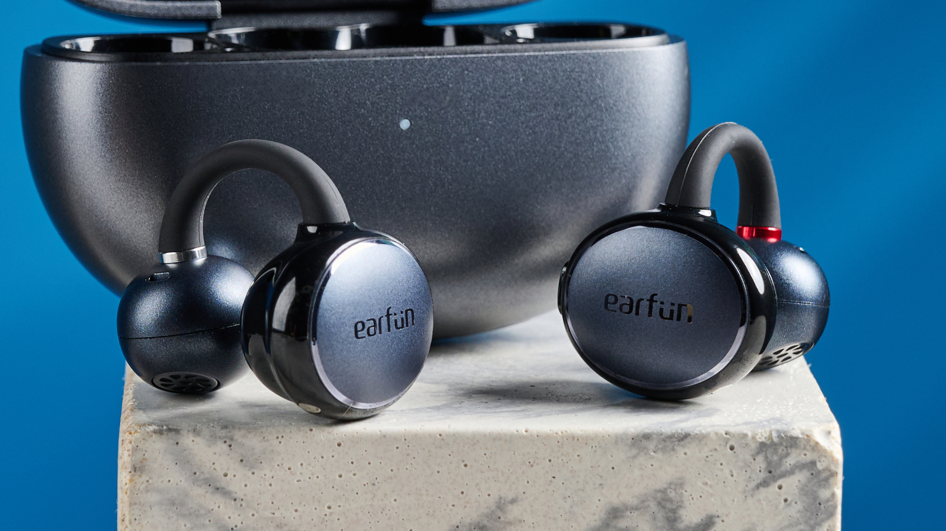 EarFun Clip open-earbuds photographed in front of a blue background.