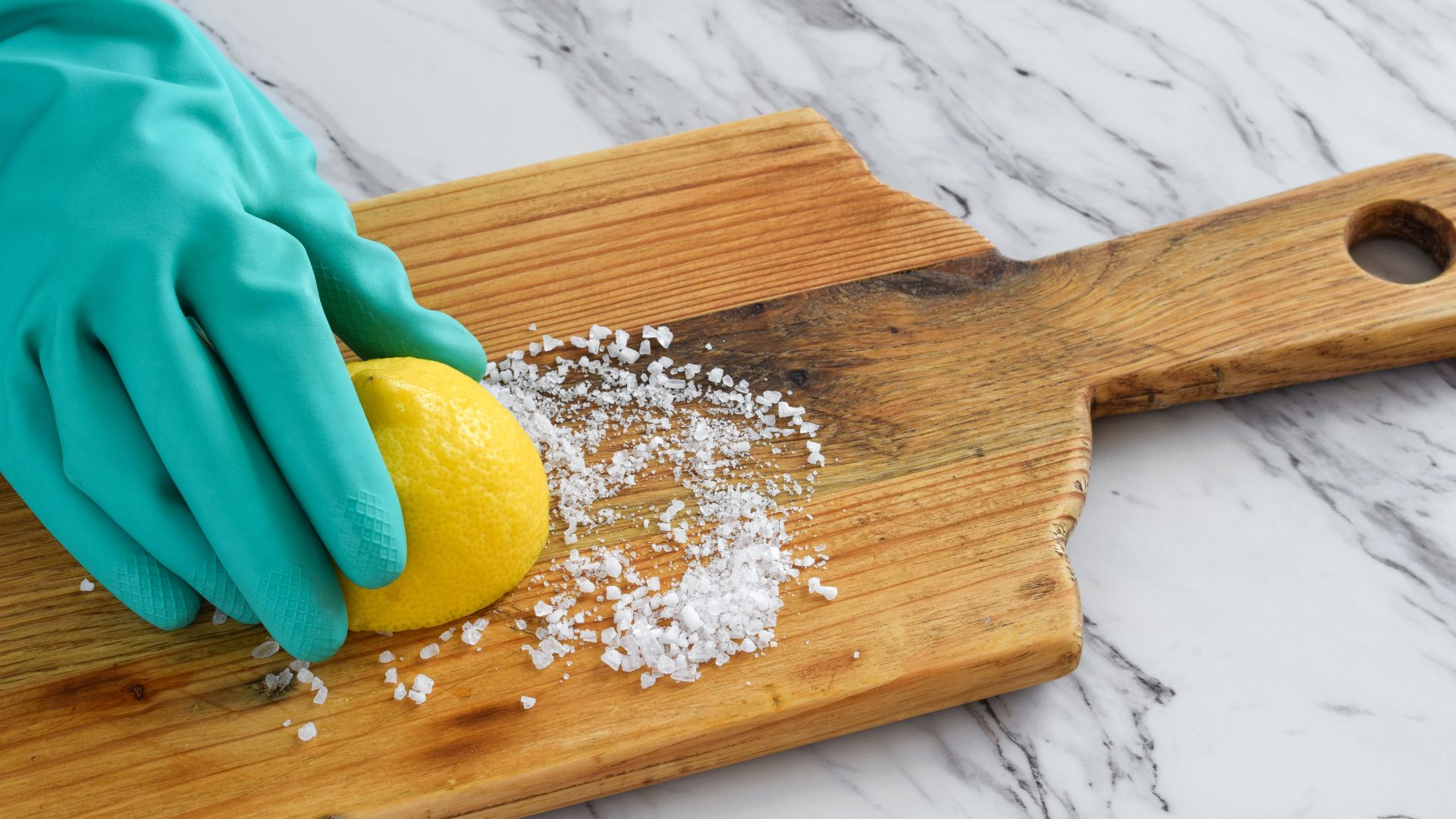 picture of woman using lemon and salt to clean wooden chopping board -