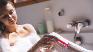 Woman shaving her legs in the bath