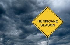 A caution sign in front of storm clouds warning of hurricane season.