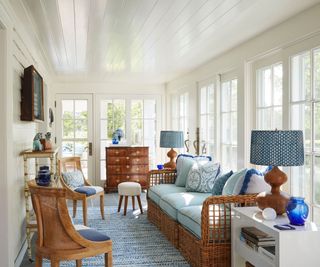 sun room with warm white walls and rattan furniture with blue cushions