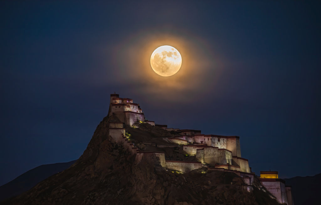 A glowing orange sphere appears over a castle on the peak of a hill