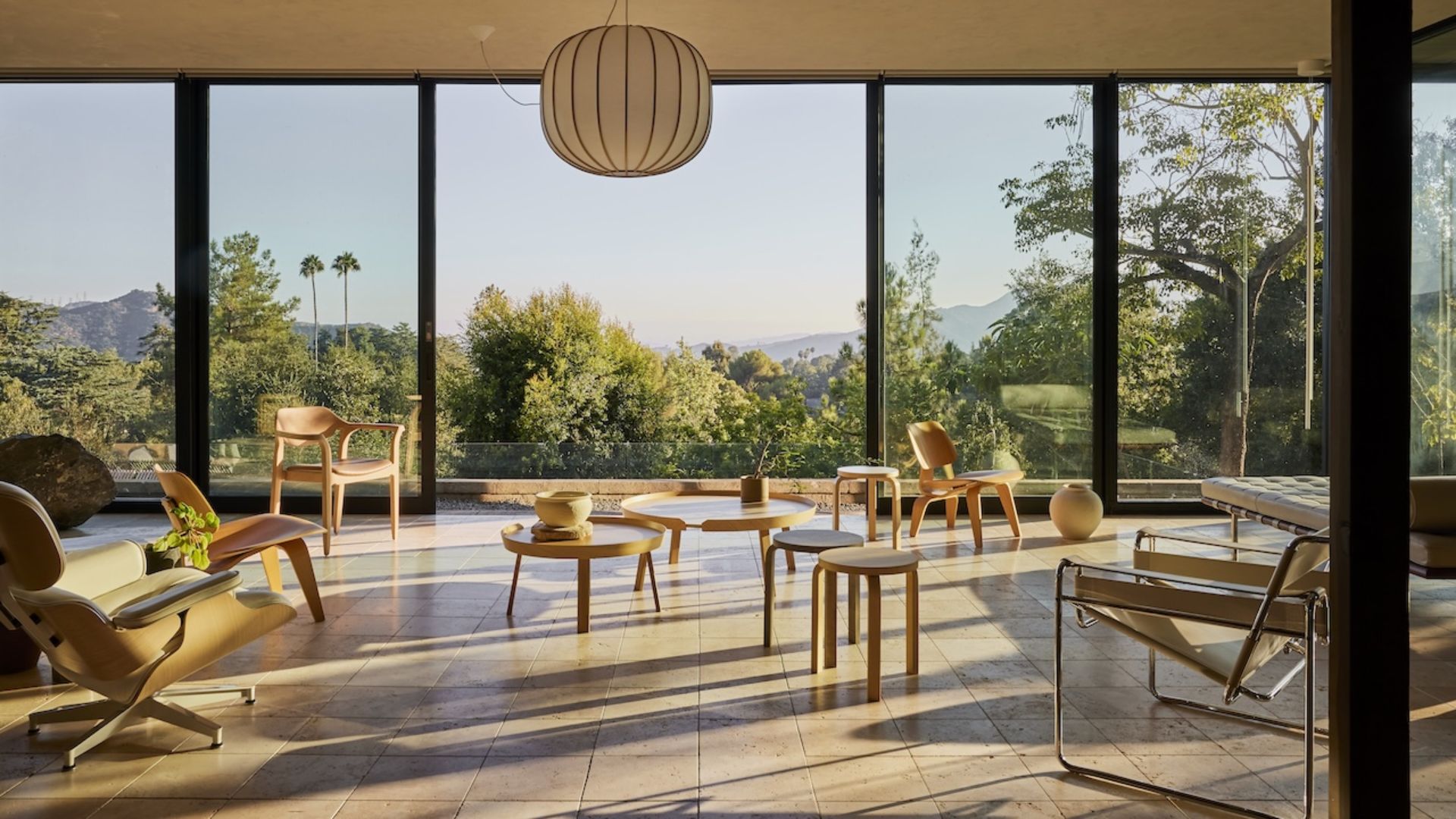 A bright living room with minimalist wood furniture and wood accents by large floor to ceiling windows