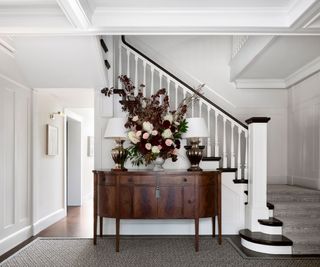 entry with dark wood sideboard and stairs with white walls