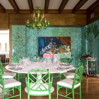 Dining room with a tropical mural, a round dining table and green chairs