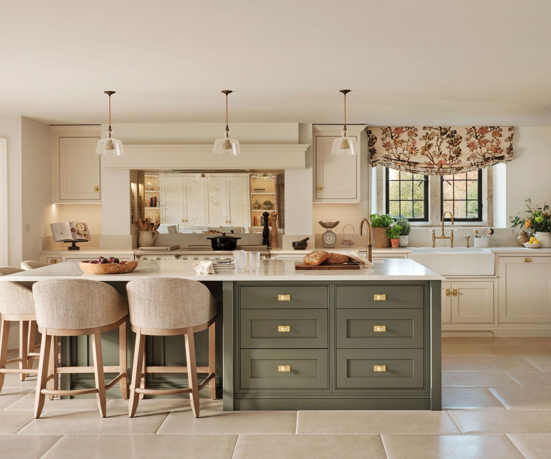 A midimalist kitchen with white cabinets, a green island, and a floral blind over the window