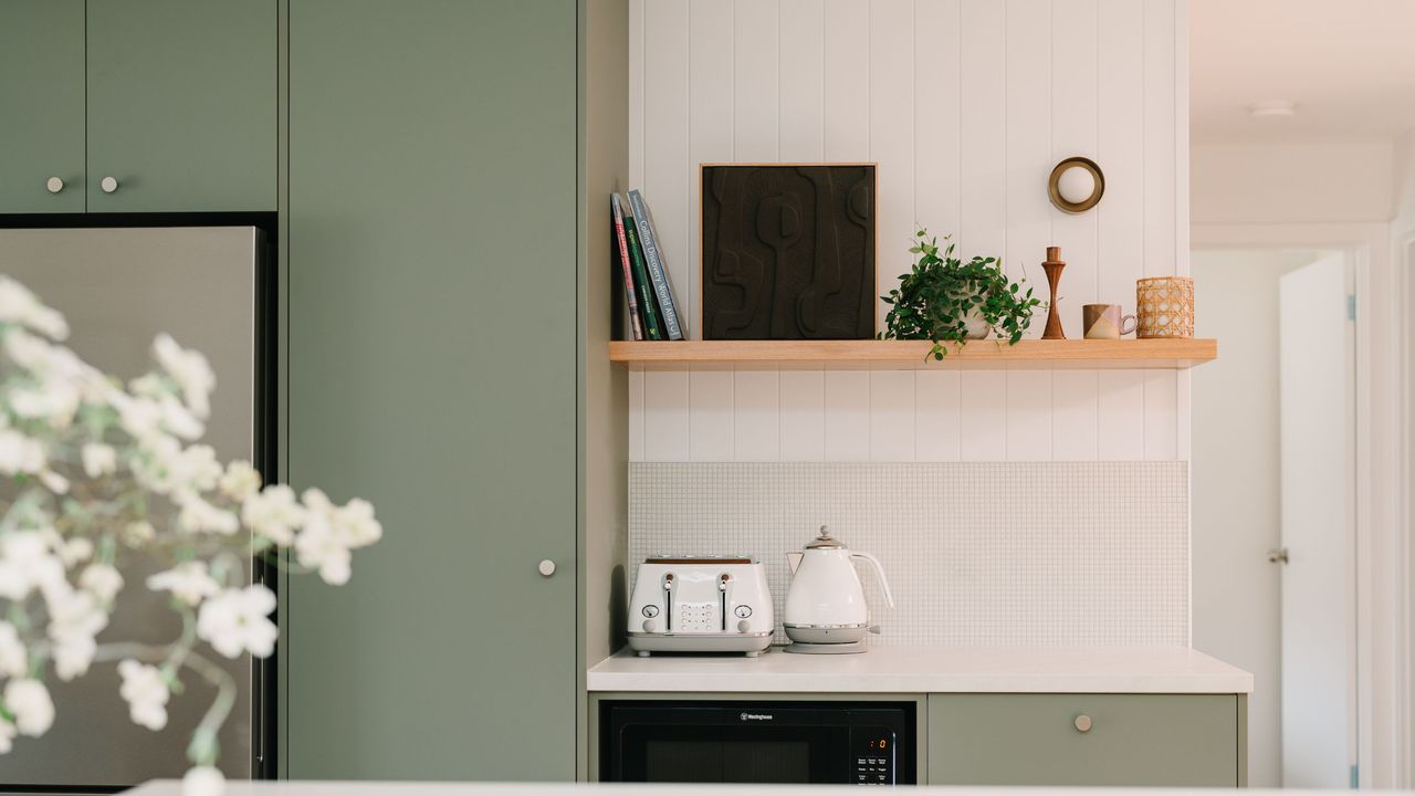 A kitchen with open shelving with lower cabinets and cupboards painted sage green. 