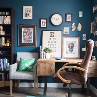 blue wall office room with wooden table brown chair ash sofa and book shelf