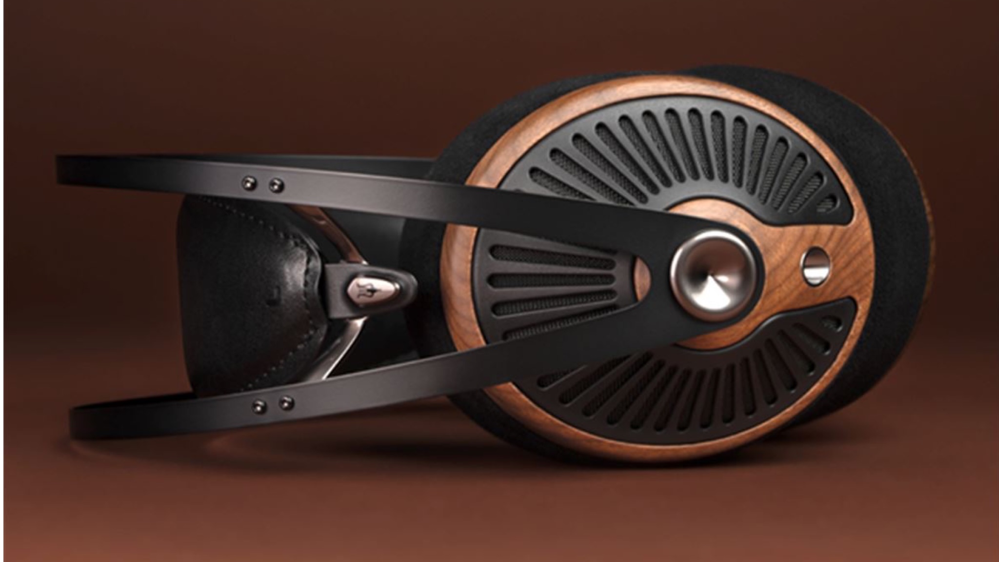 A product shot of the Meze Audio 105 Silva headphones on a brown surface with a dark brown background