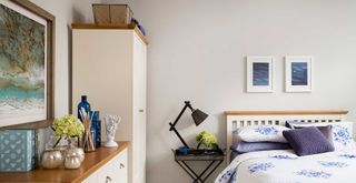 Cream bedroom with blue bedding and accessories with a tall wardrobe and chest of drawers to show how to dust a bedroom from top to bottom