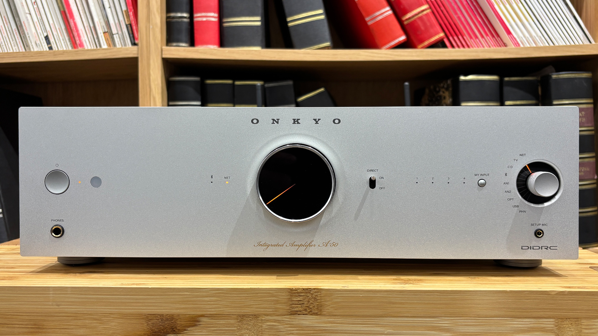 Onkyo Icon A-50 streaming amplifier on wooden hi-fi rack in front of bookcase
