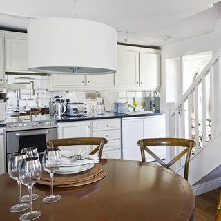 kitchen room with ceiling lamp and dining table with white plates and glasses