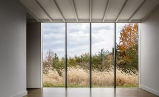 A window walled enclosed breezeway provides views and connections to the surrounding meadow