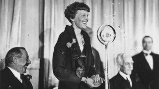 Amelia Earhart addresses journalists during lunch at the Criterion in London.