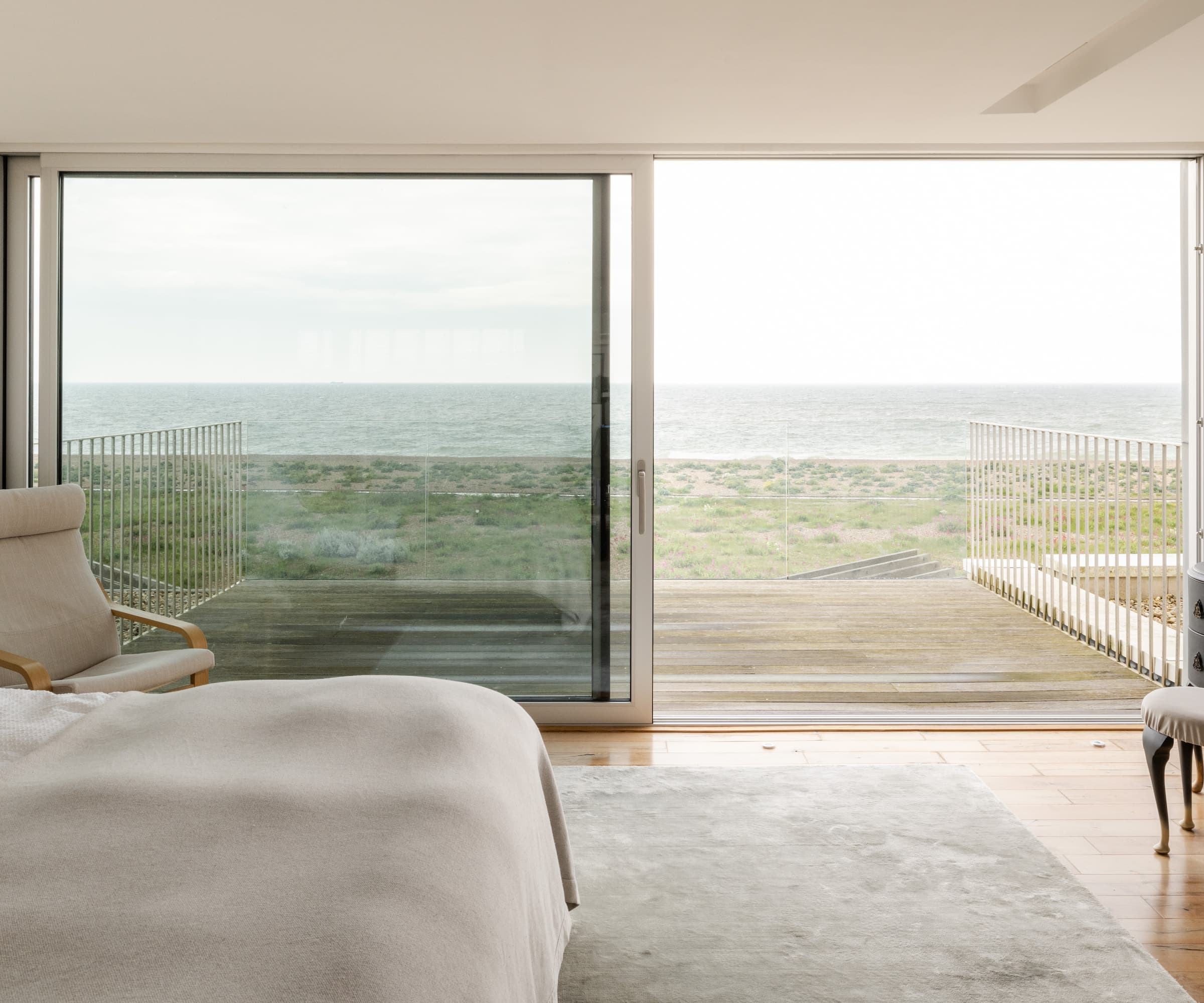 A bedroom with a view of the ocean via a bifold door