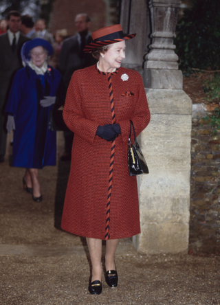 Queen Elizabeth II, wearing a red coat with red-and-black trim and a matching hat, attends the Christmas Eve service at the Church of St Mary Magdalene on the Sandringham Estate, Norfolk, England, 24th December 1989