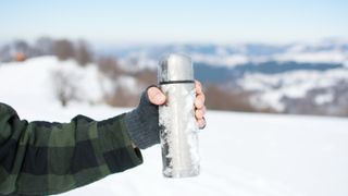 Man holding a thermos on hiking trip