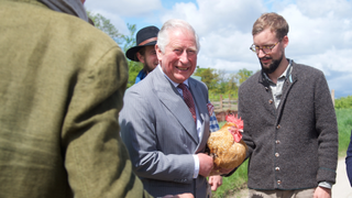 Prince Charles, Prince of Wales, holds a chicken alongside Sophie Schweinsfurth and Mathias Stinglwagner during a visit to the organic farm Herrmannsdorfer Landwerkstaetten on May 10, 2019 in Glonn near Munich, Germany