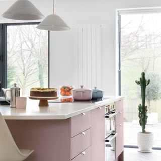 Pink kitchen island with white marble top and overhead lights