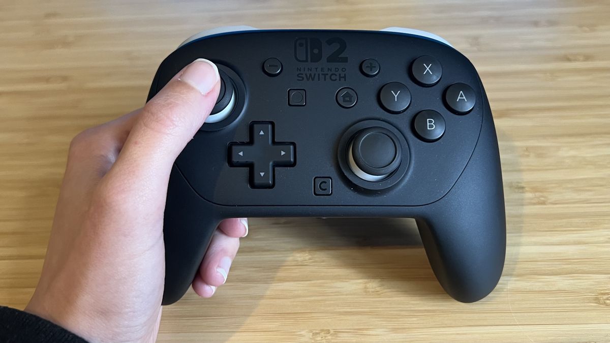 Hand holding Nintendo Switch 2 Pro Controller with thumb on thumbstick