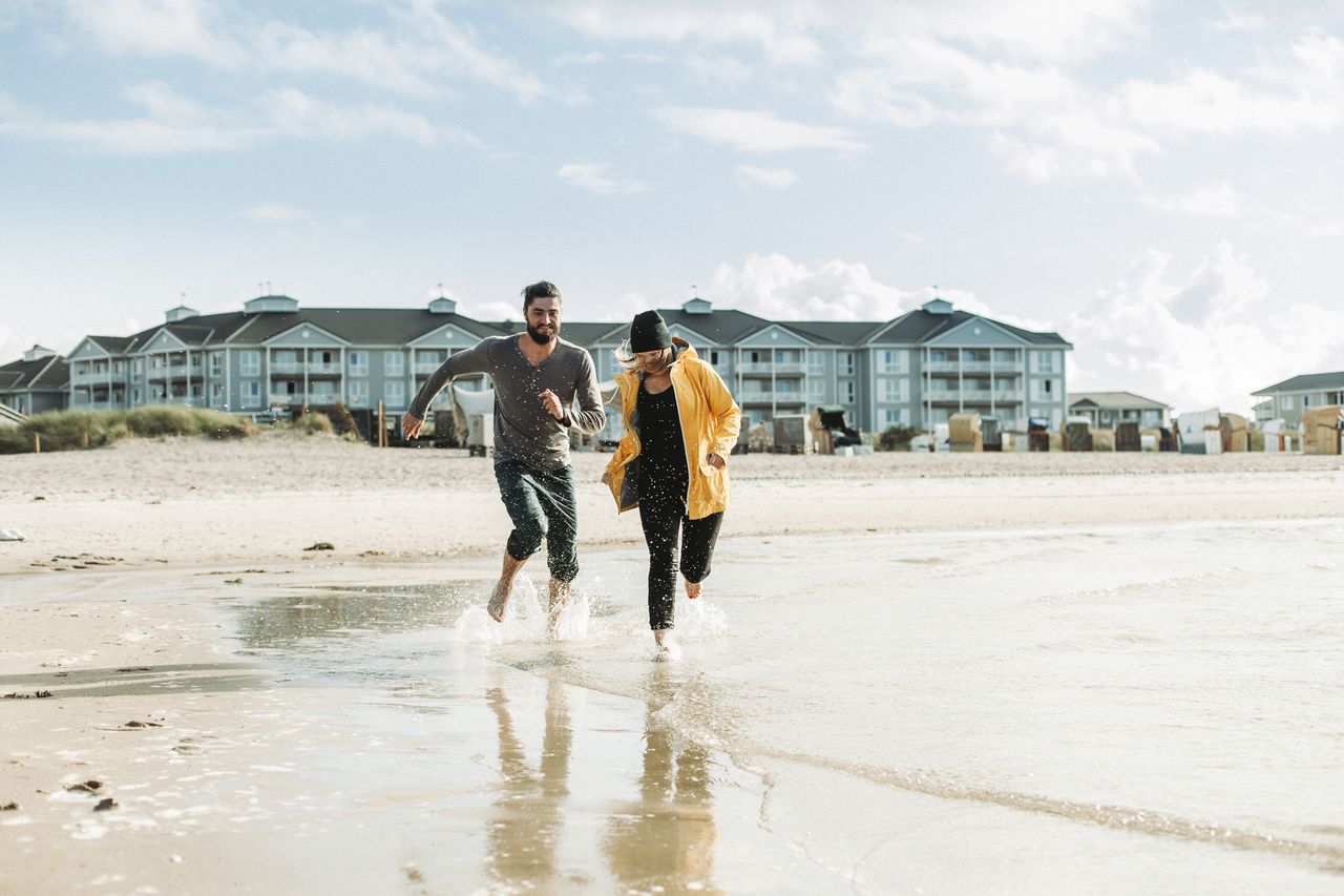 Couple running down the beach after leaving hotel in lockdown