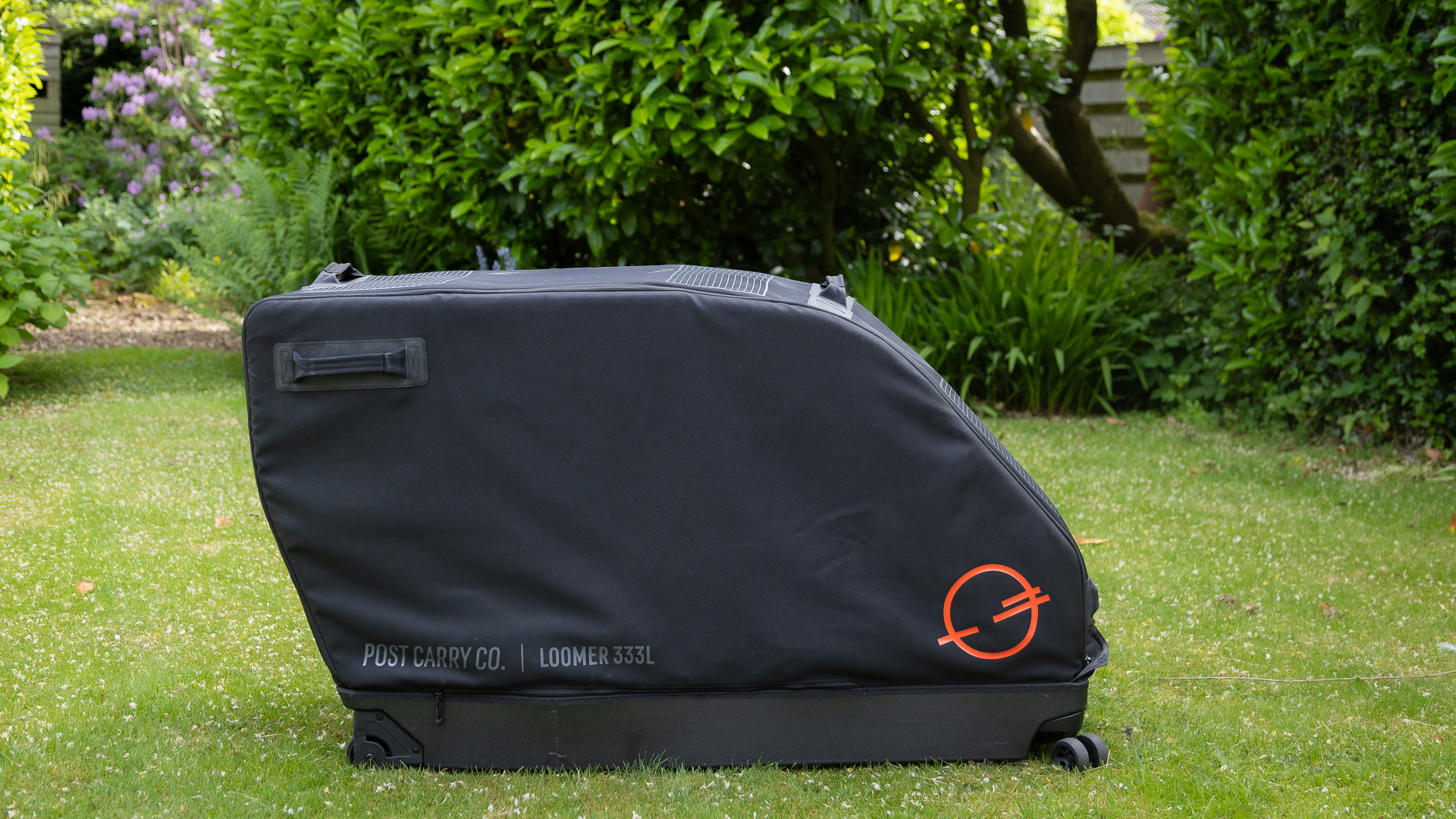 black bike box standing on a lawn with bushes behind